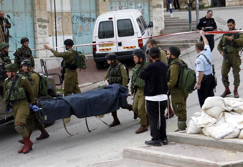 Soldados israelíes trasladan los cadáveres de los dos palestinos abatidos el 25 de marzo en Hebrón. / EFE