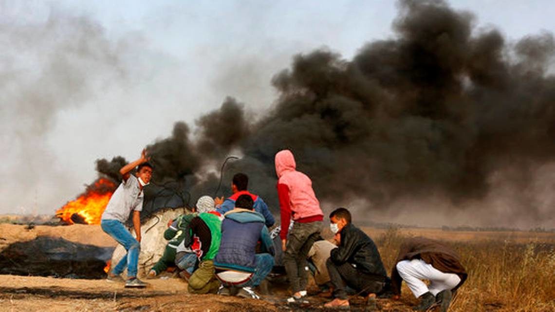 Manifestantes palestinos se ponen a cubierto durante enfrentamiento con las tropas israelíes junto a la frontera entre Gaza e Israel, al este de Khan Younis, en la Franja de Gaza, el 5 de abril de 2018.