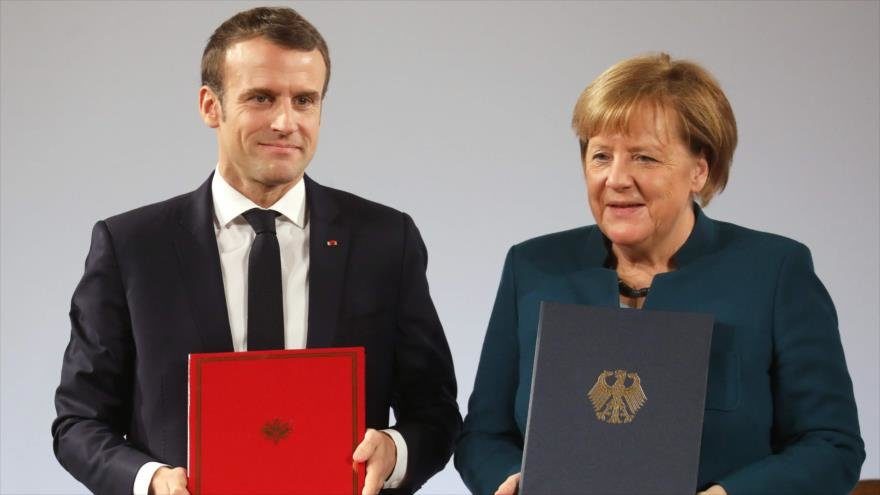 El presidente francés, Emmanuel Macron (dcha.), y la canciller alemana, Angela Merkel, posan con el tratado de amistad en Aquisgrán, 22 de enero de 2019.