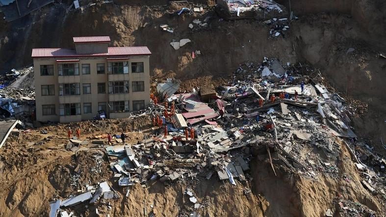 Rescue workers are seen at the debris of collapsed houses