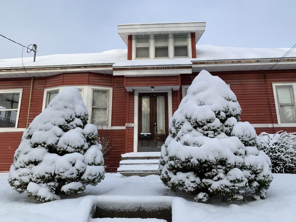 Snow covers shrubs in front of this home