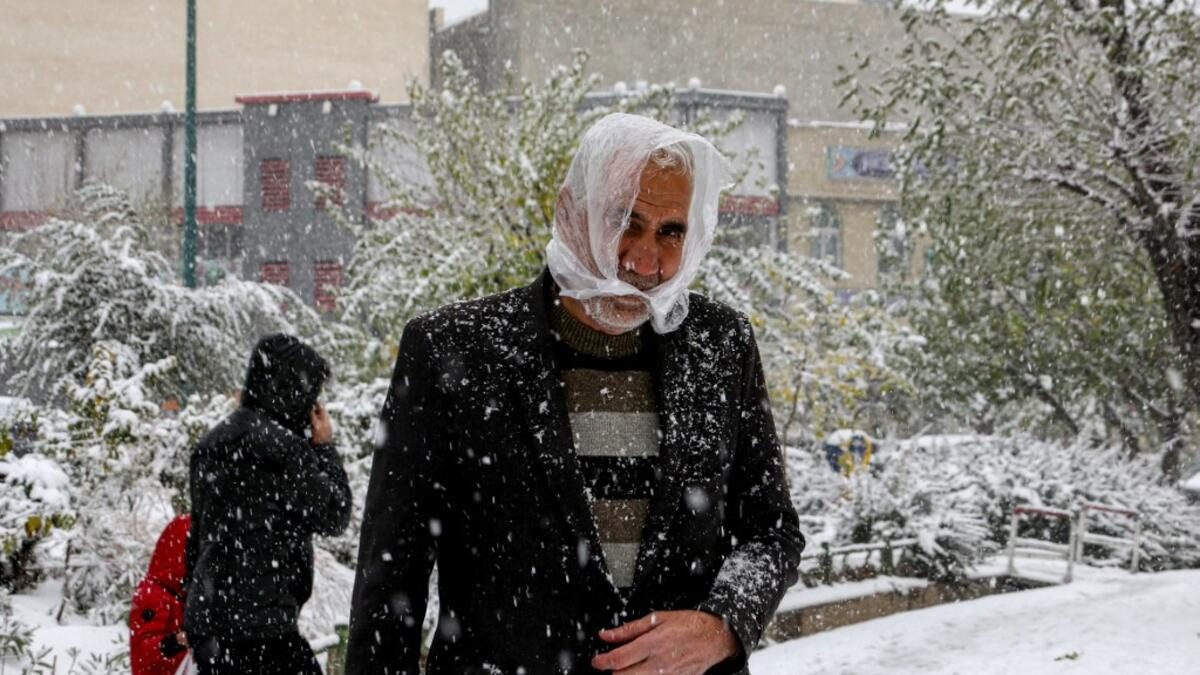 People walk under heavy snow in the Iranian capital Tehran on November 16, 2019.