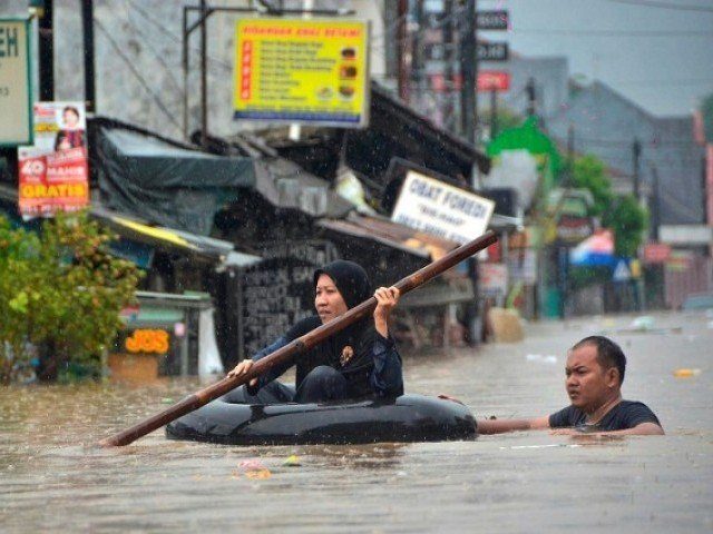 A woman paddles through flood waters on an inner tube in Bekasi, near Jakarta.