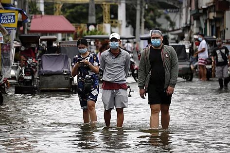 Tres personas caminan en las calles inundadas de Macabebe (Filipinas).