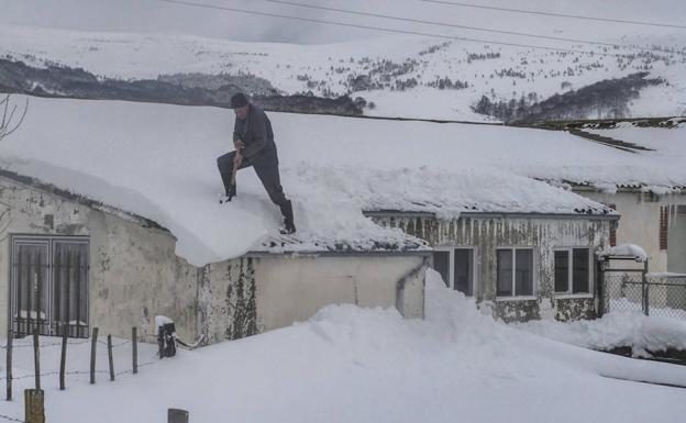 Un vecino de Campoo retira la nieve del tejado de su nave.