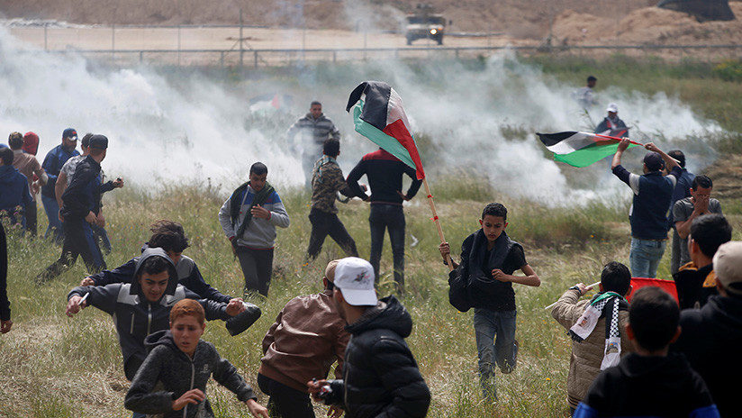 Palestinos huyen del gas lacrimógeno lanzado por las tropas israelíes durante los enfrentamientos en la frontera de Gaza, el 30 de marzo de 2018.