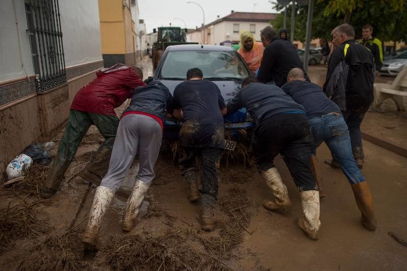 Vecinos de Campillos empujan un coche afectado por las inundaciones en Málaga