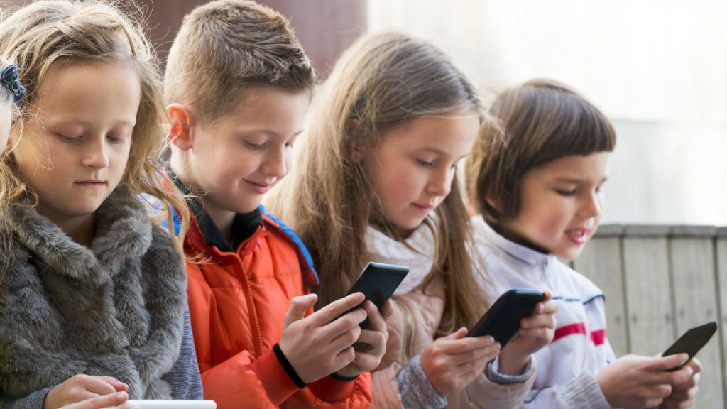 niños usando teléfonos móviles