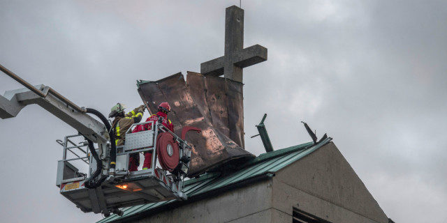 Firefighters in Frankfurt try to secure the tin roof of a church tower in the district of Gallus