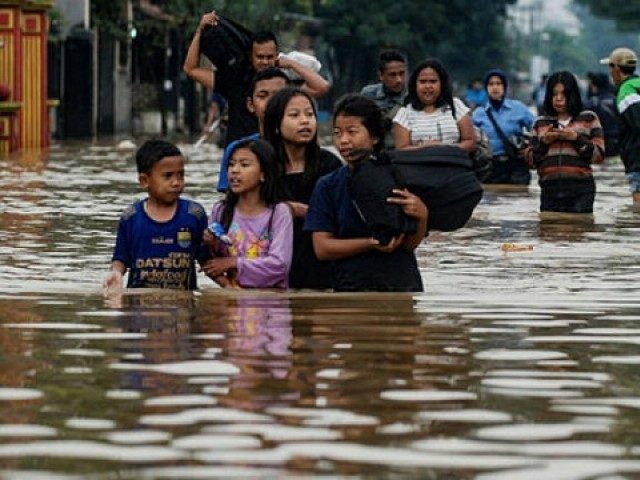 Residentes caminan por una carretera inundada mientras se evacuan de la aldea de Dayeuhkolot en Bandung.