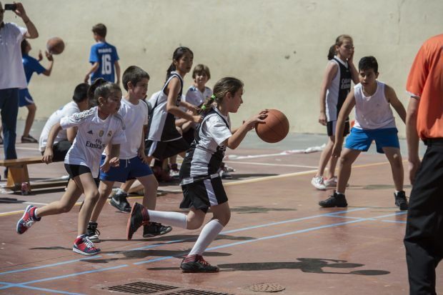 Niños y niñas juegan juntos al baloncesto.