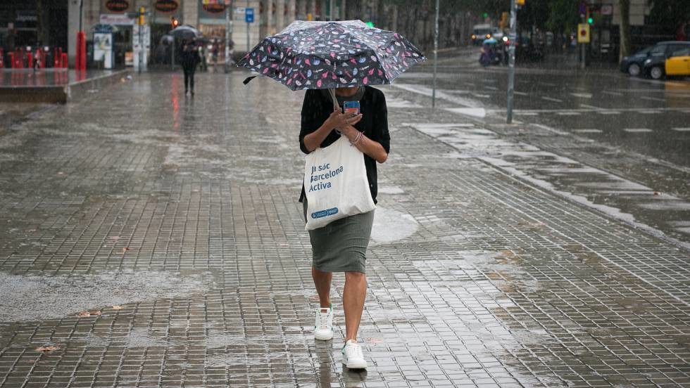 Una mujer se protege de la lluvia en Barcelona. foto: Albert Garcia