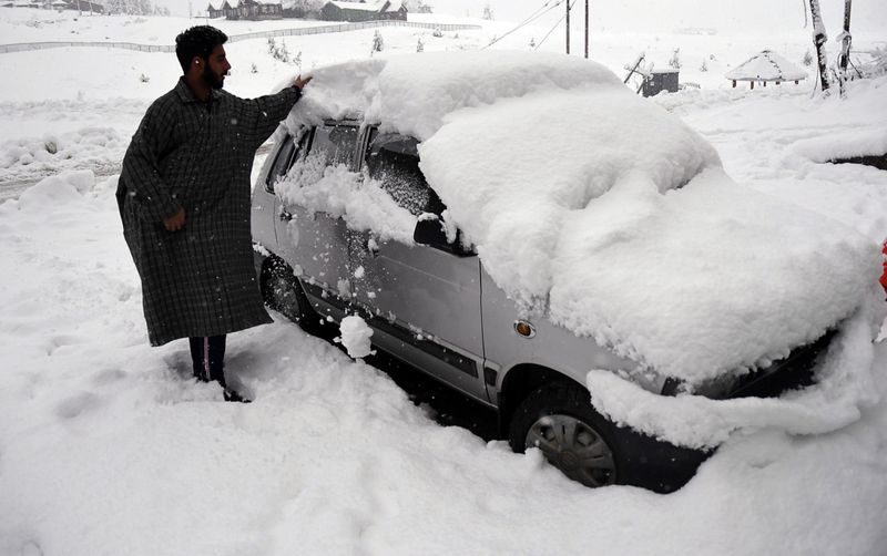 A man removing snow from a car during the first snowfall of the season in Gulmarg. While the snowfall has been moderate in the plains of Kashmir, the upper reaches have witnessed heavy snowfall.