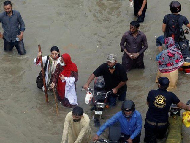 People wade through a flooded road during monsoon rain in Karachi, Pakistan.