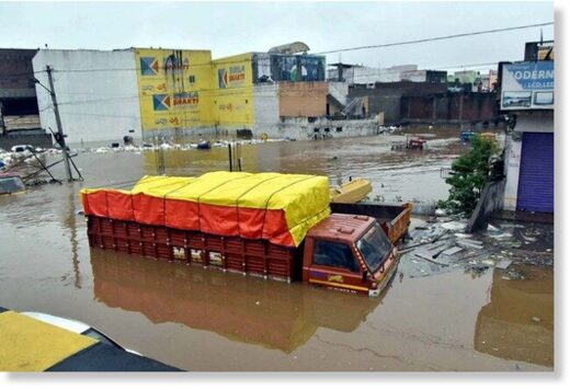 Vehicles lie partially submerged in floodwater following heavy rains, at Falaknuma, in Hyderabad.