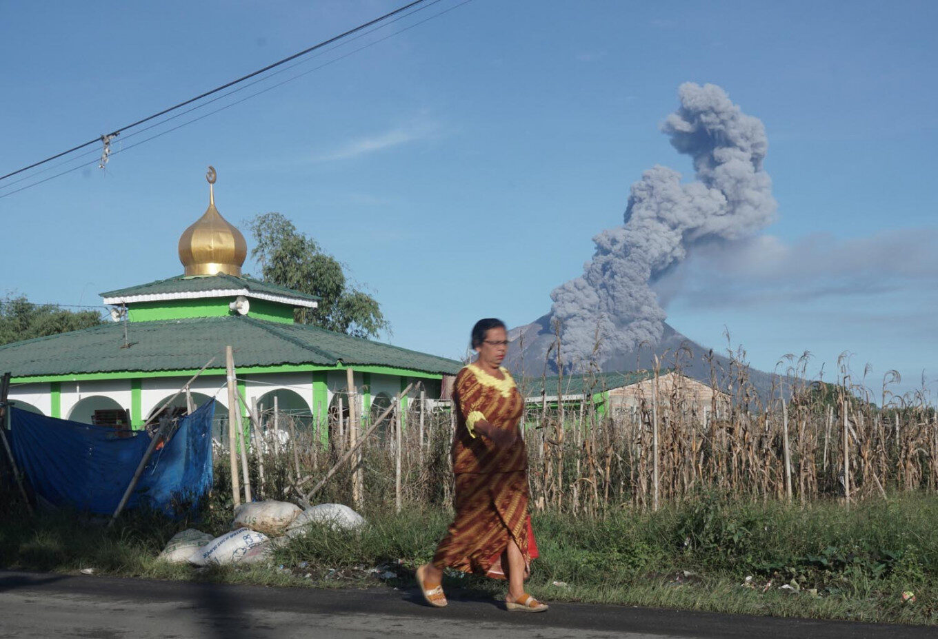 A woman walks as Mount Sinabung spews