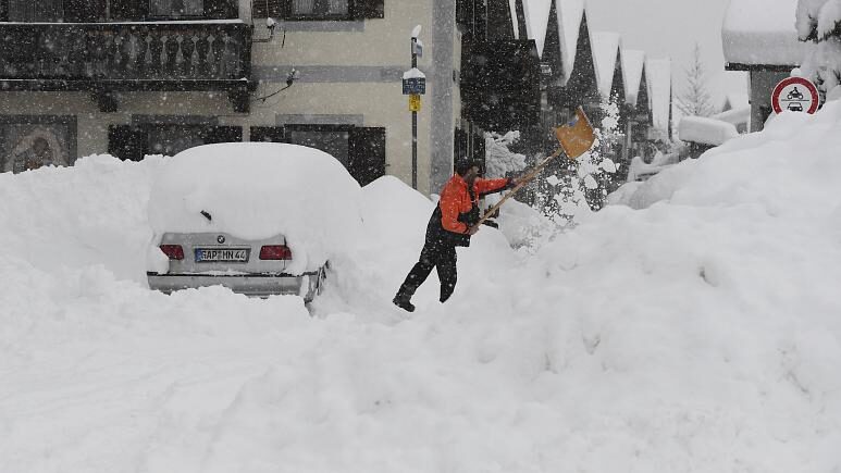 A man shovels his car free of snow after days of snowfall in Garmisch-Partenkirchen, southern Germany, Monday, Jan. 18, 2021.   -