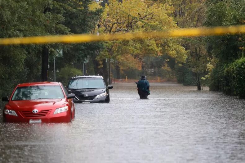 A pedestrian walks on a flooded street on