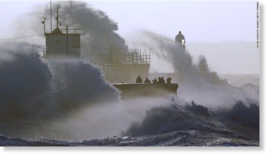 Waves crash against the sea wall and Porthcawl Lighthouse in Bridgend, Wales, as Storm Eunice hits the UK on Friday.