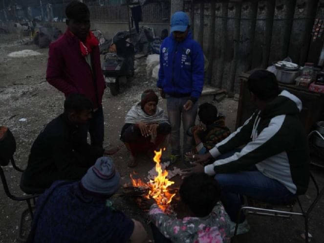 People sit around a bonfire to warm themselves during a cold winter morning, in New Delhi