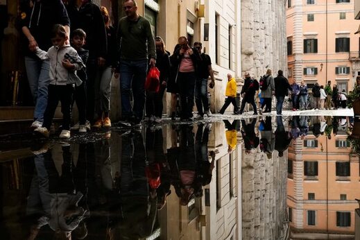 Personas cruzan un charco después de fuertes lluvias en el centro de Roma, el martes 2 de mayo de 2023.