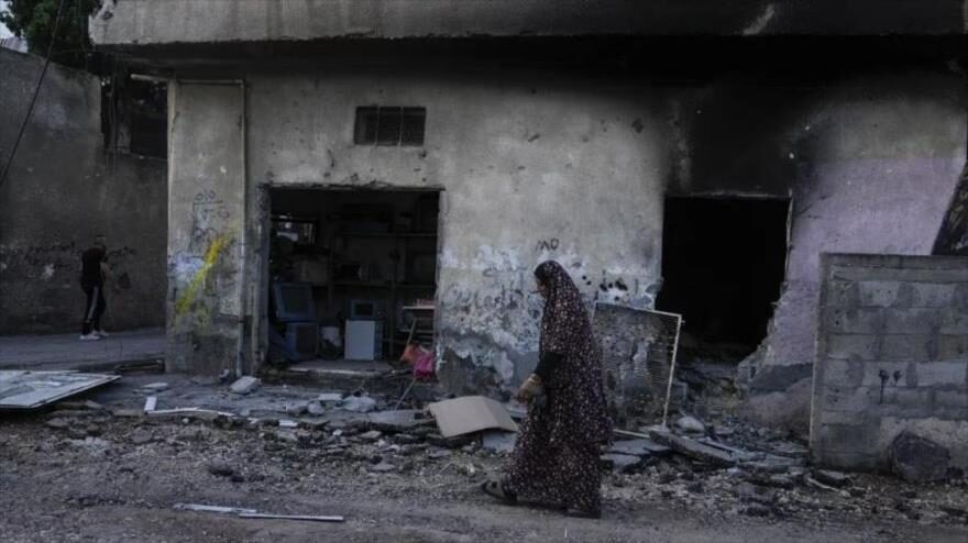 Una mujer palestina camina por una carretera dañada por una ofensiva israelí en el campo de refugiados de Yenín, 5 de julio de 2023