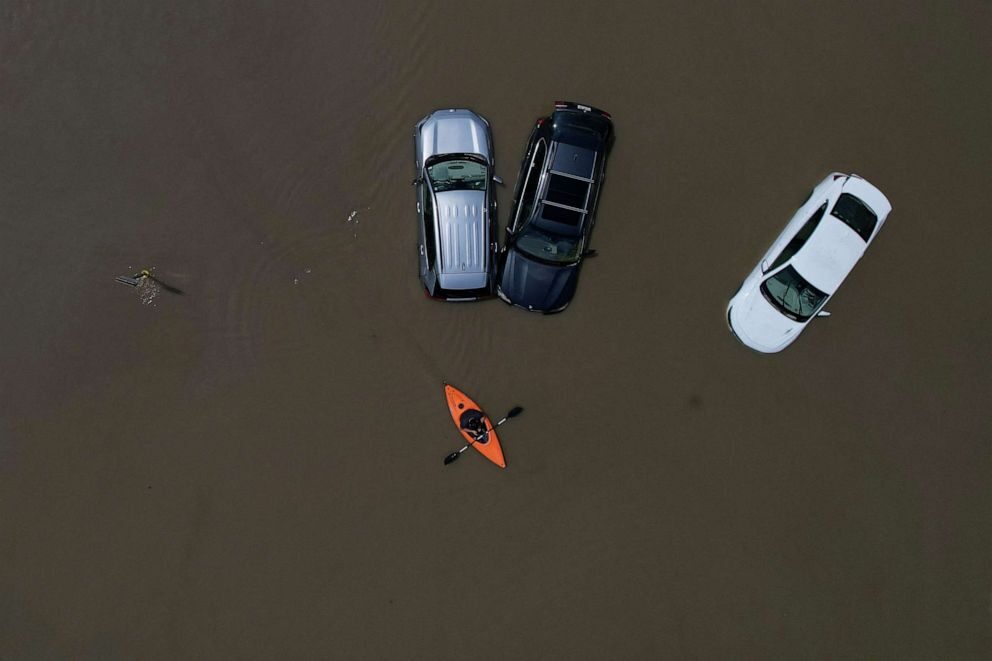 A person in a canoe passes parked cars partially submerged by floodwaters from recent rainstorms in Montpelier, Vermont, on July 11, 2023.