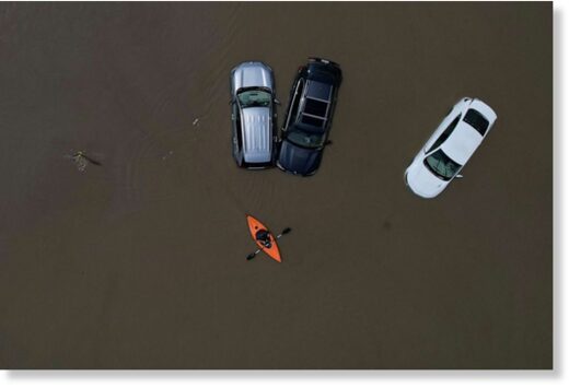 A person in a canoe passes parked cars partially submerged by floodwaters from recent rainstorms in Montpelier, Vermont, on July 11, 2023.
