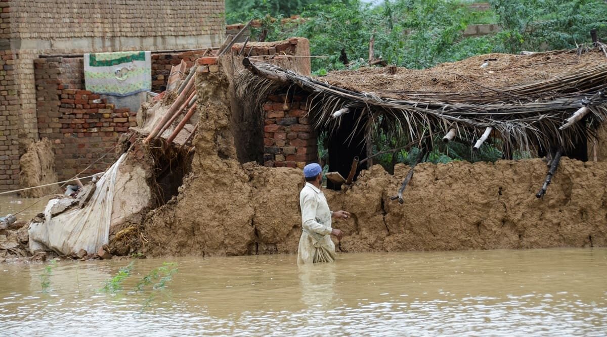 A man wades through flood waters beside his damaged house following rains and floods during the monsoon season in Dera Allah Yar, district Jafferabad, Balochistan, Pakistan on August 25, 2022.