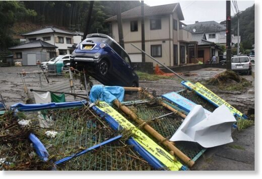 A car is seen resting next to a toppled fence in the wake of Typhoon Yun-yeung following flooding of a river in the Fukushima Prefecture city of Iwaki on Sept. 9, 2023.