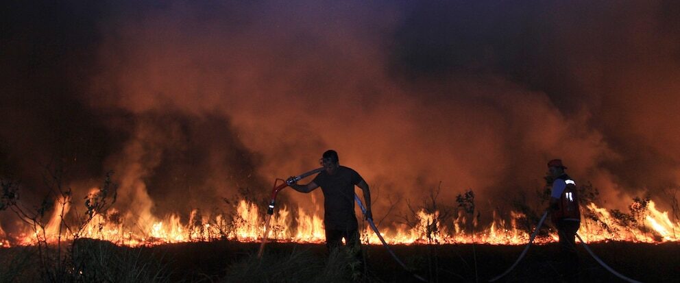 Firefighters attempt to extinguish a fire that razes through a peatland field in Ogan Ilir South Sumatra, Indonesia, Tuesday, Sept. 12, 2023.