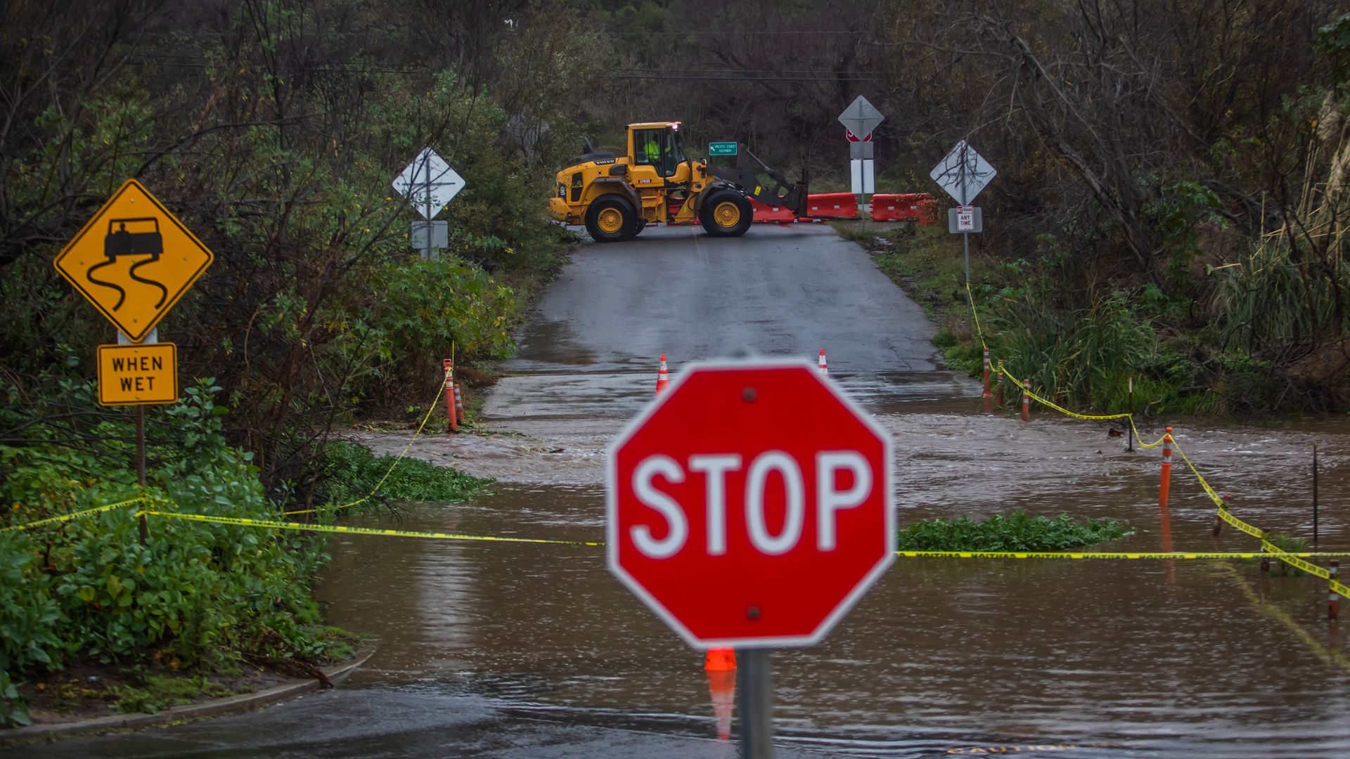 City workers close a road after a creek overflows during heavy rains in Zuma Beach on December 21, 2023 in Malibu, California.