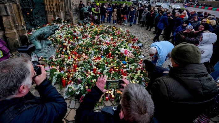 Un grupo de personas deposita flores a la entrada de una iglesia cerca de un mercado navideño, donde un coche arrolló a una multitud el viernes por la noche, en Magdeburgo, Alemania