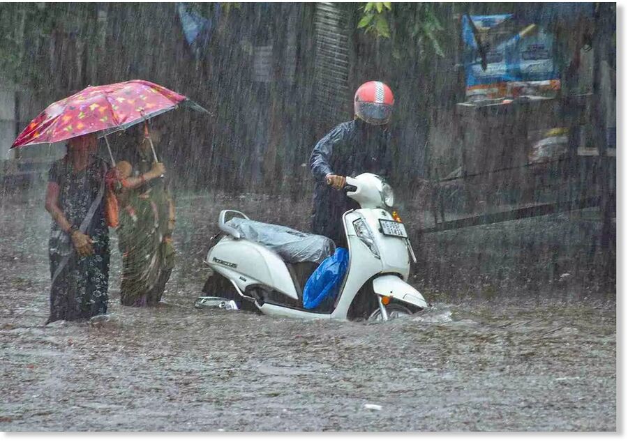 Commuters wade through a waterlogged