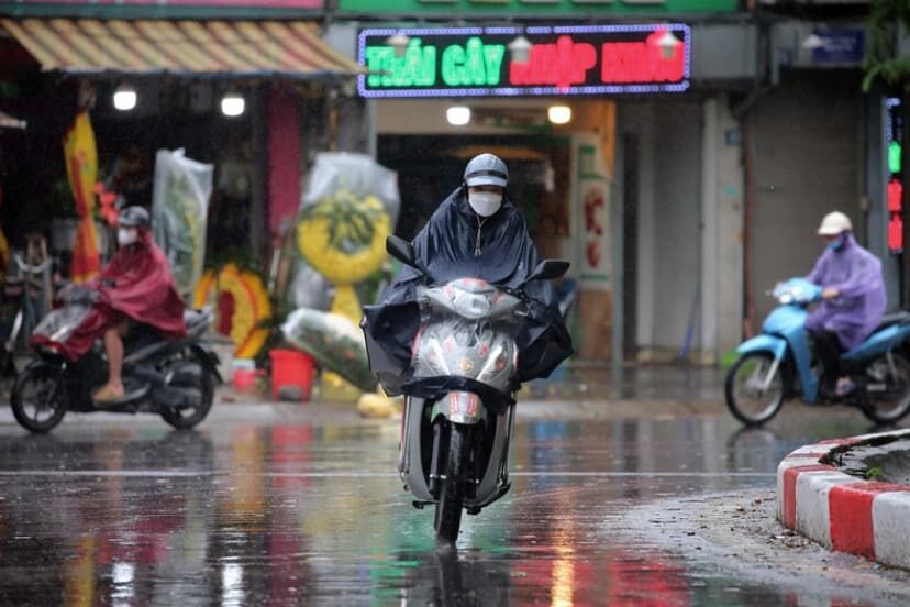 Personas en motocicletas bajo la lluvia en Hanói, Vietnam,