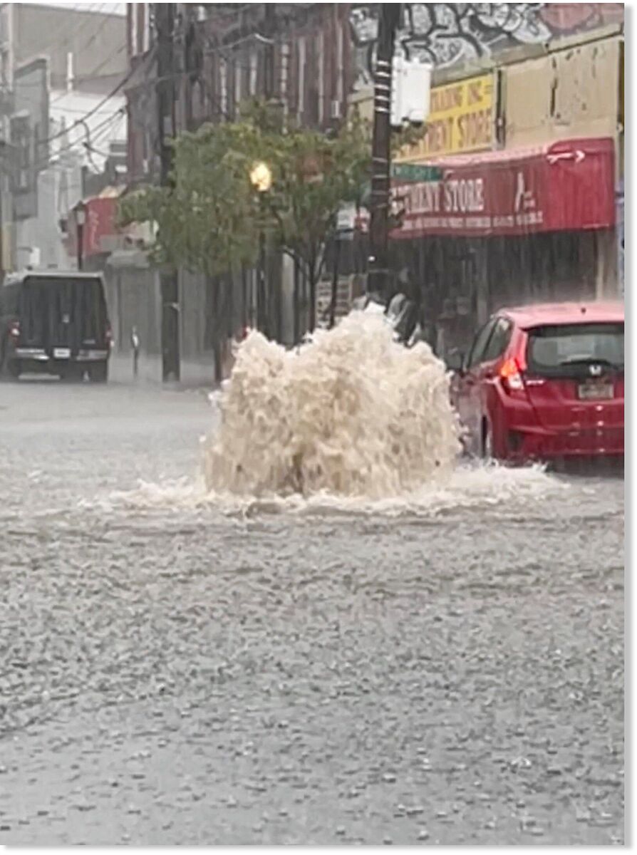 A car drives on a flooded street after heavy downpours in Staten Island, New York on Thursday