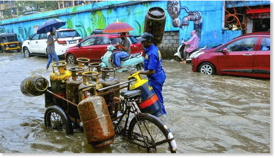 A man with a cylinder cart wades through a waterlogged road following heavy rainfall, in Nala Sopara, on August 16, 2025.