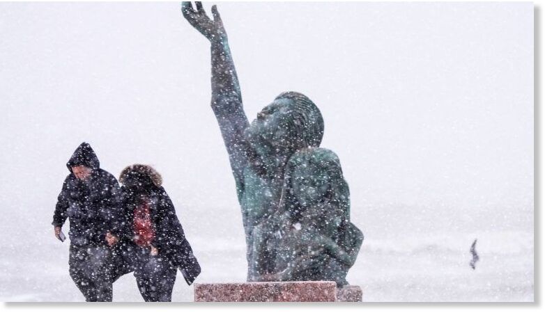 People walk past the 1900 Storm memorial sculpture on Seawall Blvd. during an icy winter storm on Jan. 21, 2025, in Galveston, Texas.
