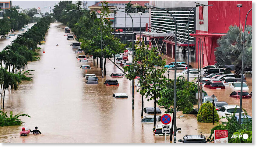 People wade through floodwaters near inundated vehicles in Nha Trang on November 20, 2025 [