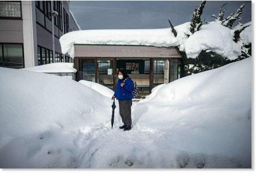 A passenger waits in front of a snow-covered bus stop in the city of Aomori on Friday.