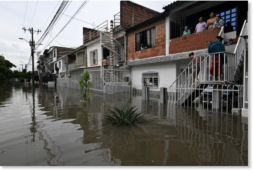 People stare at the flooded street after heavy rains.