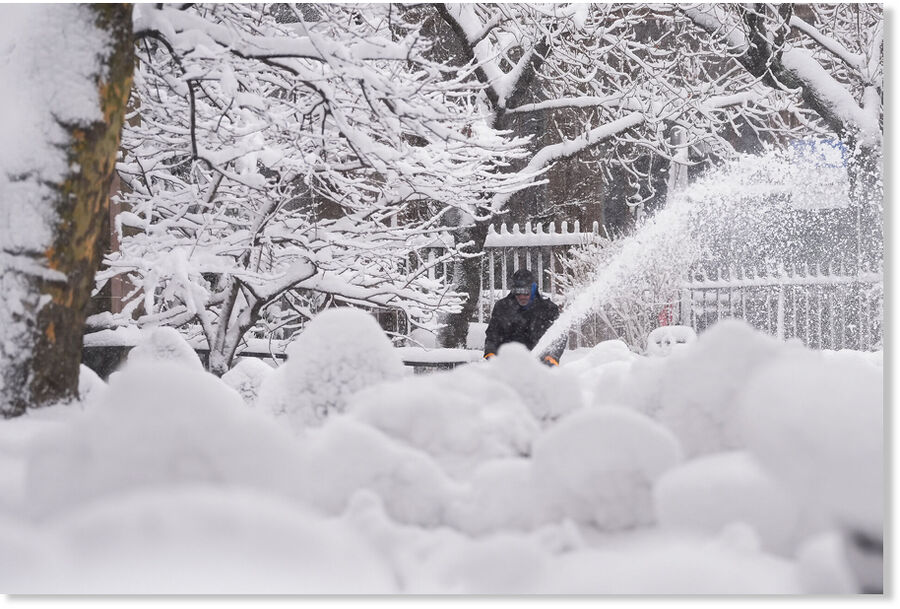 A groundskeeper clears snow from the walkways inside the Trinity Church graveyard in lower Manhattan during a snow storm, Monday, Feb. 23, 2026, in New York.