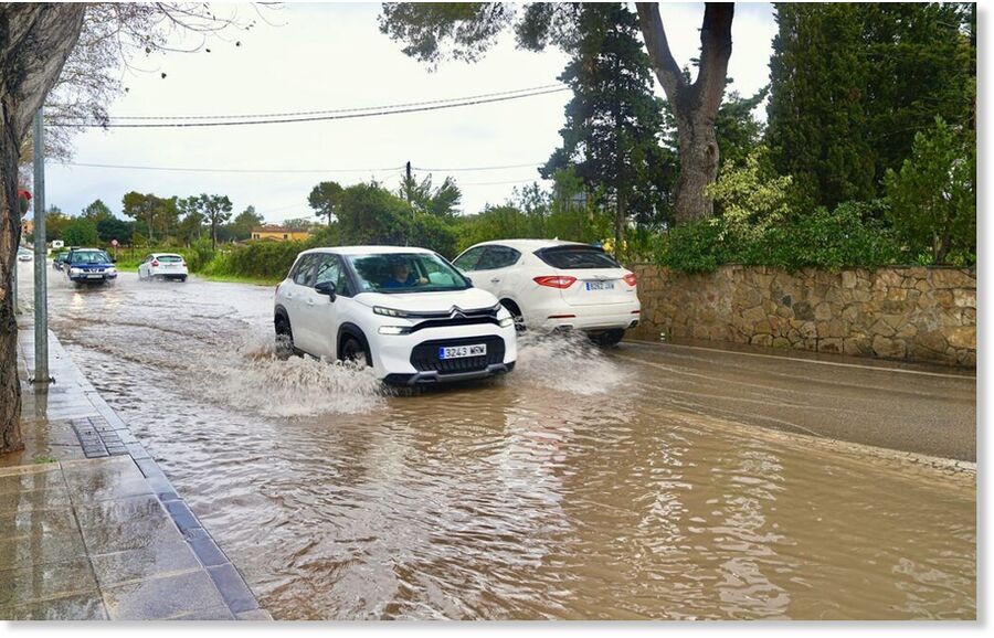 Vehicles drive through floodwater on a street in Spain after record winter storms brought the heaviest rainfall in nearly 50 years.