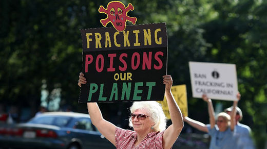 Protestors hold signs against fracking